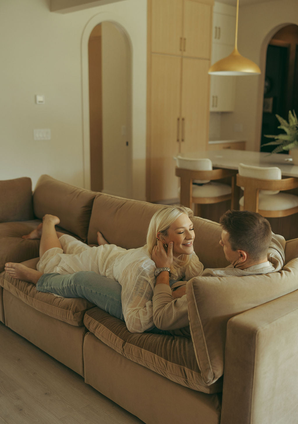 A couple photographed on the living-room sofa by the window