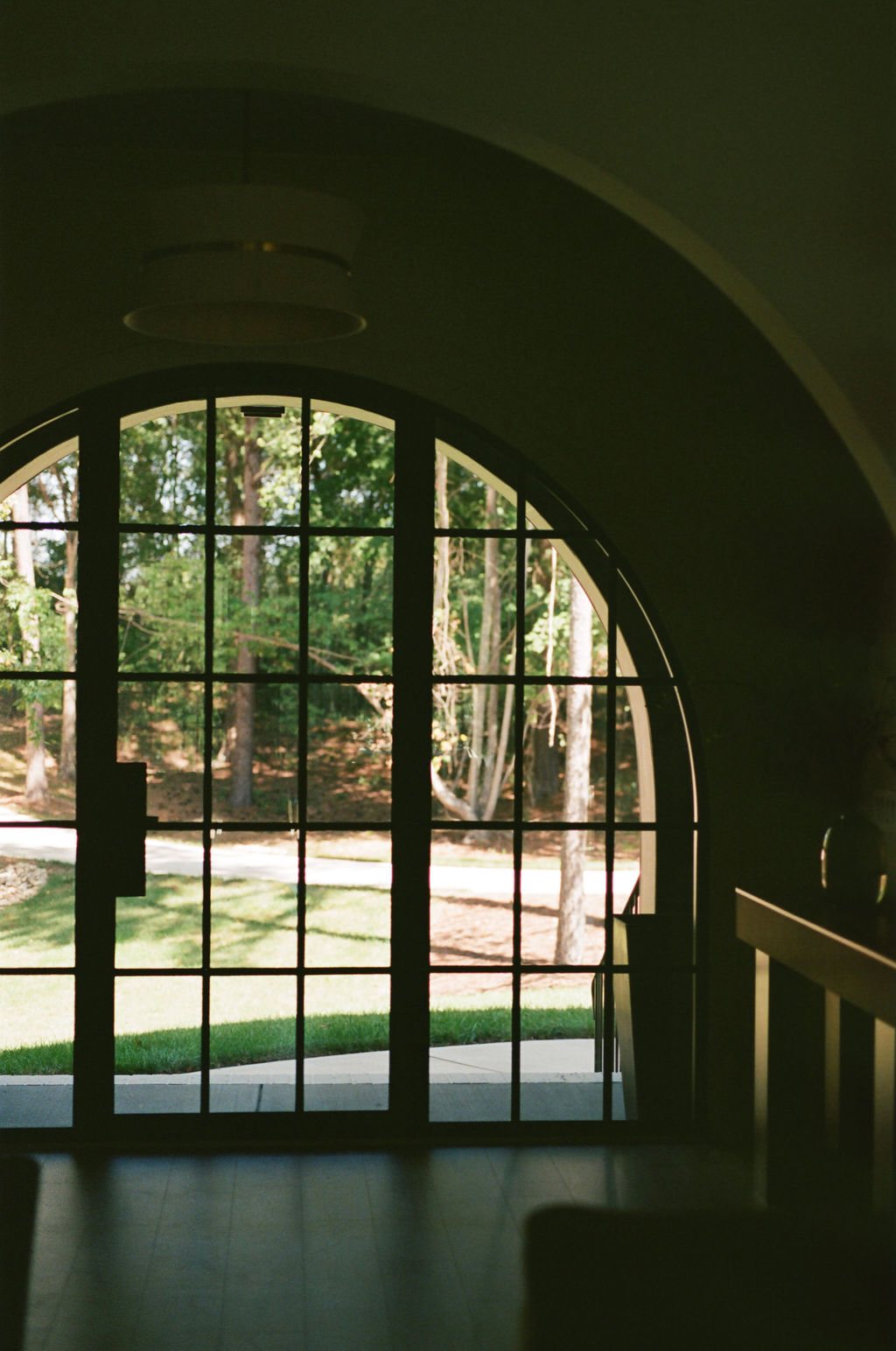 The arched entry from inside: the steel-framed glass door and the trees beyond