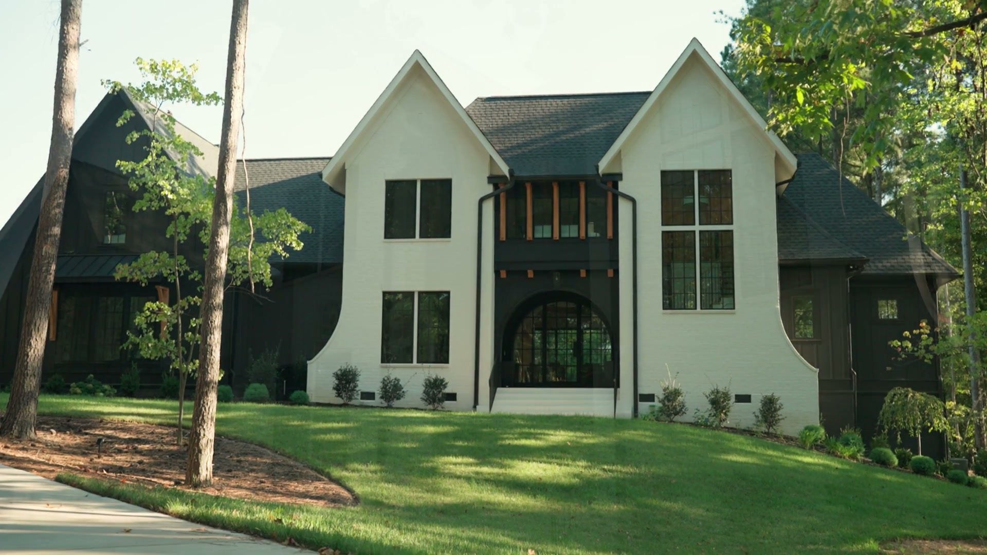 The front of the house: white gables with dark trim, a steep roof and the arched entry