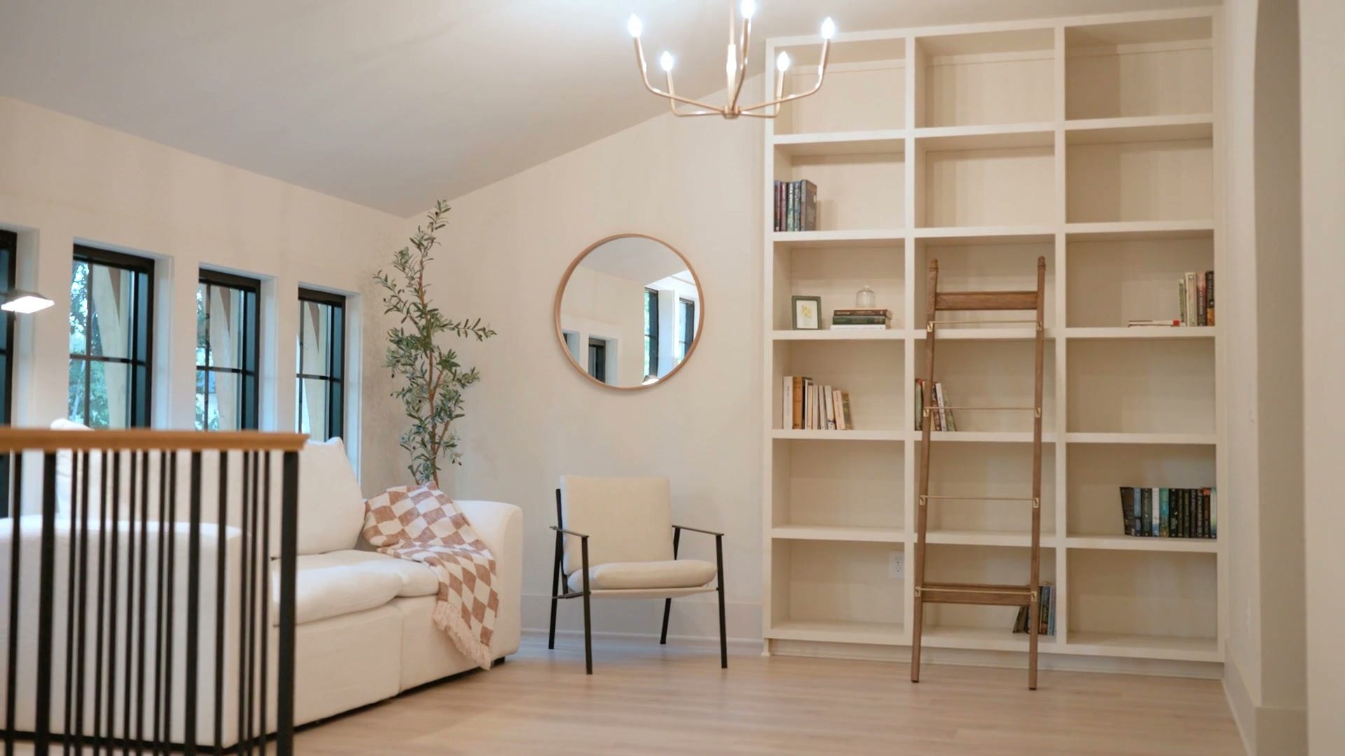 The library: white shelving with the rolling oak ladder, the windows beside it over a pale wood floor