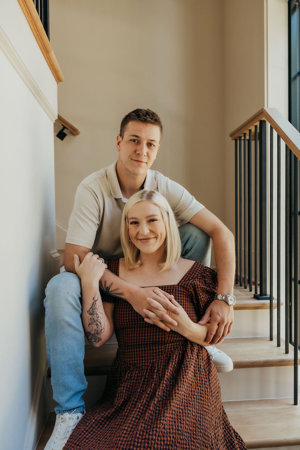 A couple photographed on the staircase, the black iron rail behind them