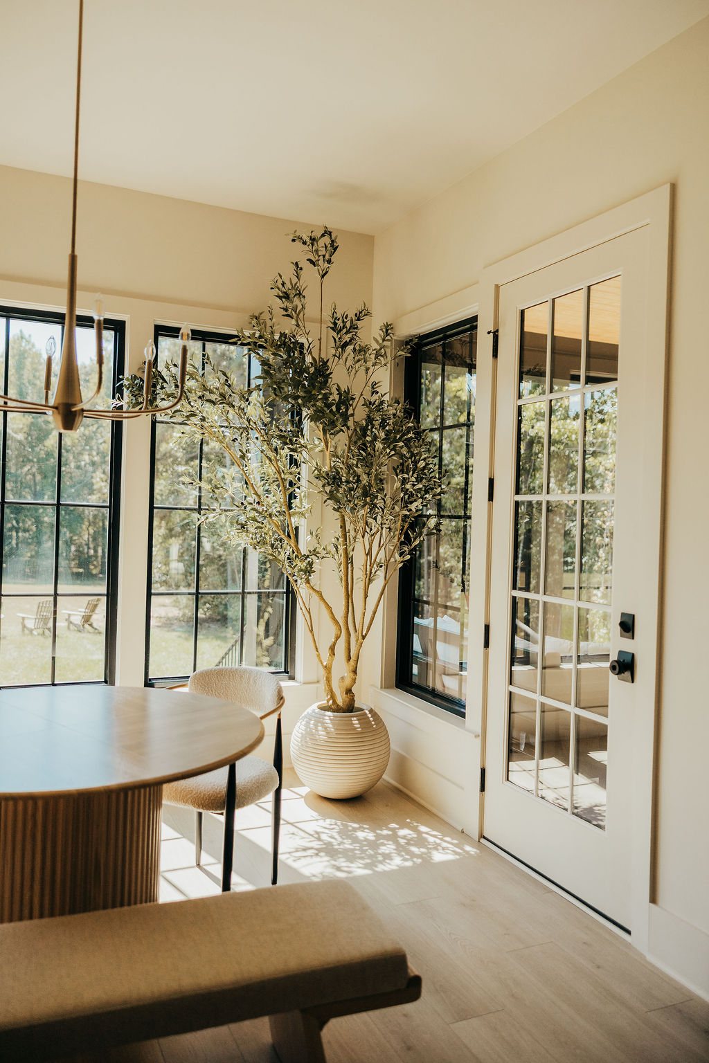The dining nook: round oak table in front of tall black windows