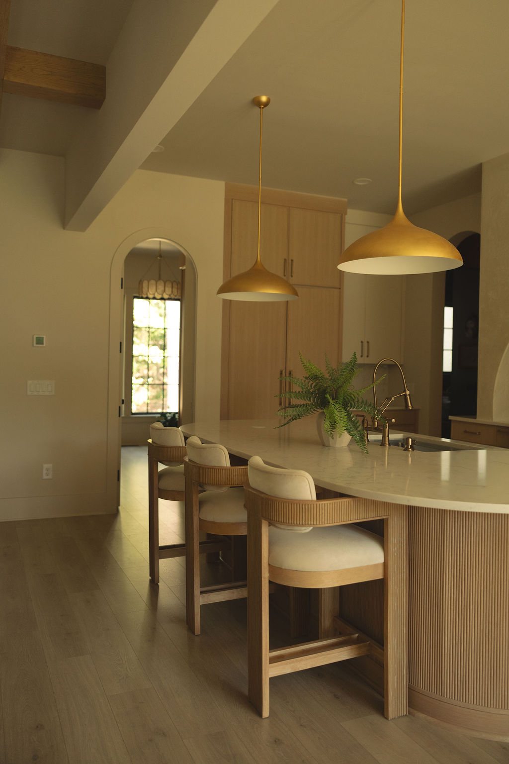 The kitchen island from the side: marble top, fluted oak base and the pendants above