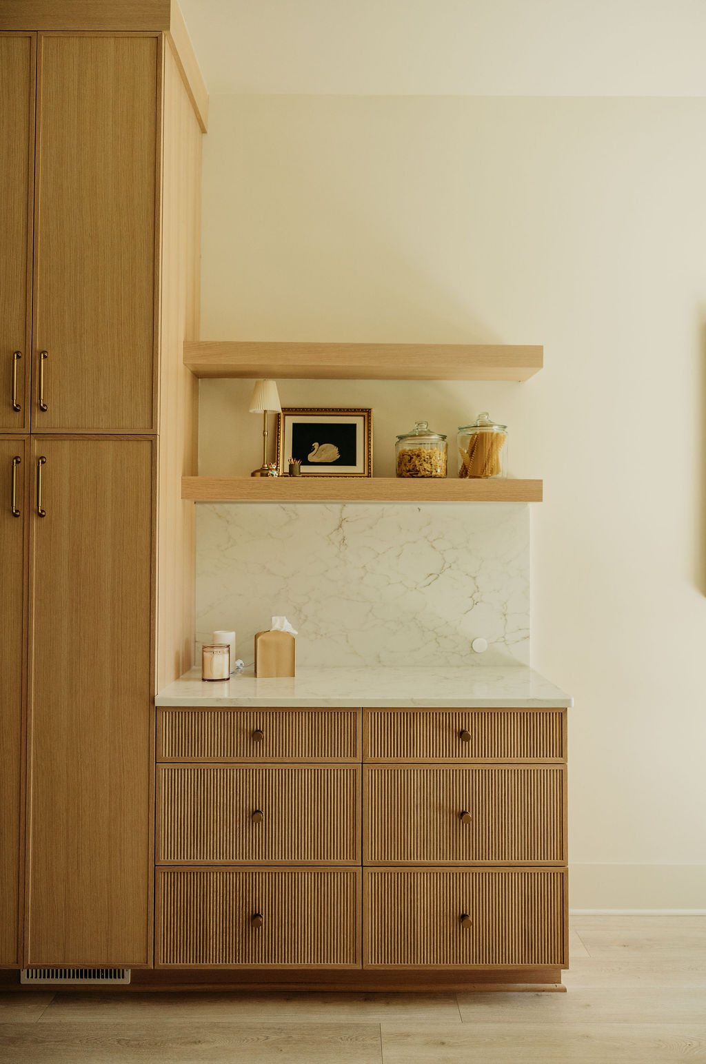 A styled shelf in the pantry: oak drawers, marble counter, ceramics