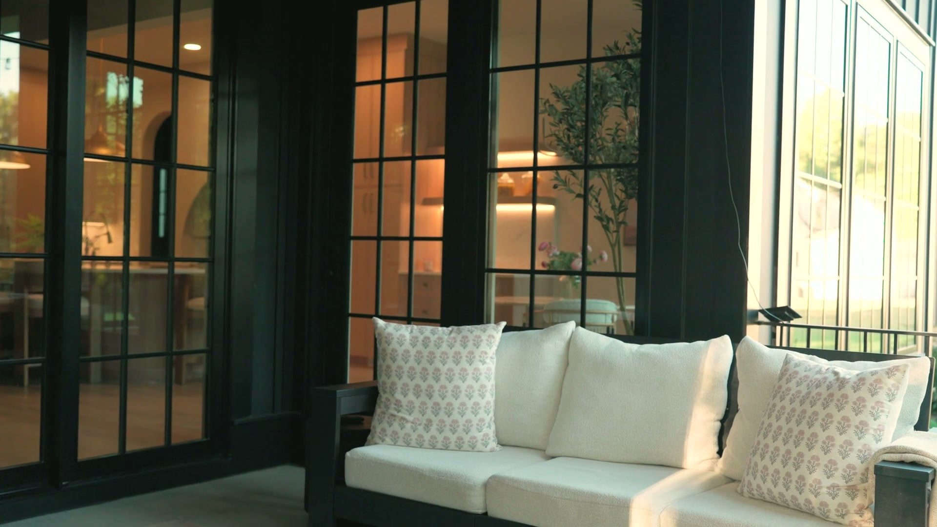 The porch sofa with patterned cushions against the black-framed windows